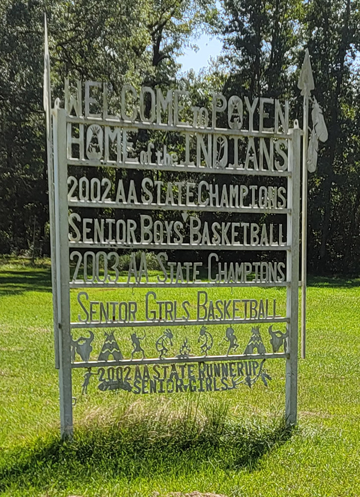 Metal sign listing team sports accomplishments with trees in background