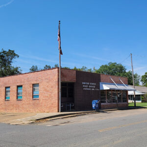 Single story red brick post office building on street corner