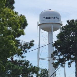 Metal water tower saying "Thornton" with trees in foreground