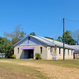 Single story tan brick church building with purple awning