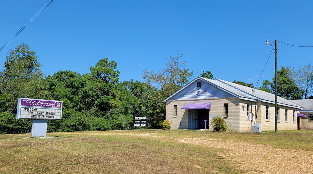 Single story tan brick church building with purple awning