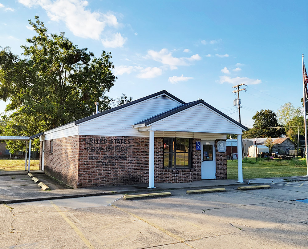 small brick building with white siding and covered entrance and parking lot