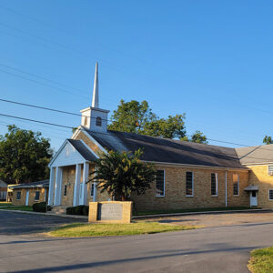 Multistory blond brick church building with white steeple