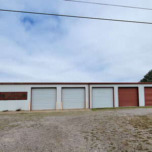 Single story white metal building with six garage doors.
