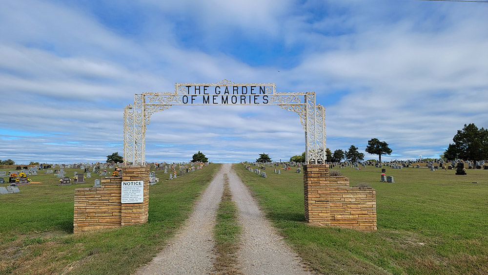 Cemetery with arched entrance and gravestones and long gravel path