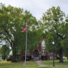 Multistory red brick courthouse building with trees and flagpole in foreground