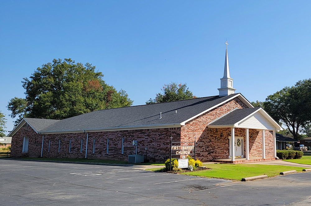 Single story brick church building with white covered entrance