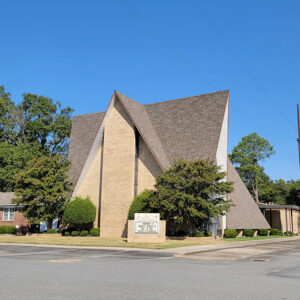 Multistory tan brick geometrically shaped church building on street corner