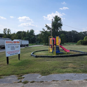 Children's playground equipment next to a picnic pavilion and a sign saying "Marvell Fun Park"