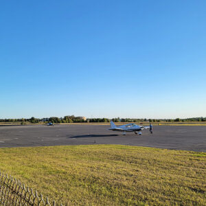 Small planes on a concrete apron with chain link fence in foreground