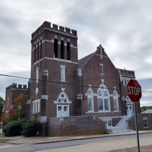 large multistory red brick church building with arched windows and multiple entrances