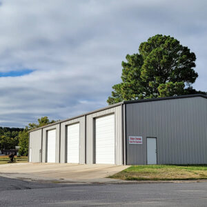 Single story gray metal building with four garage doors