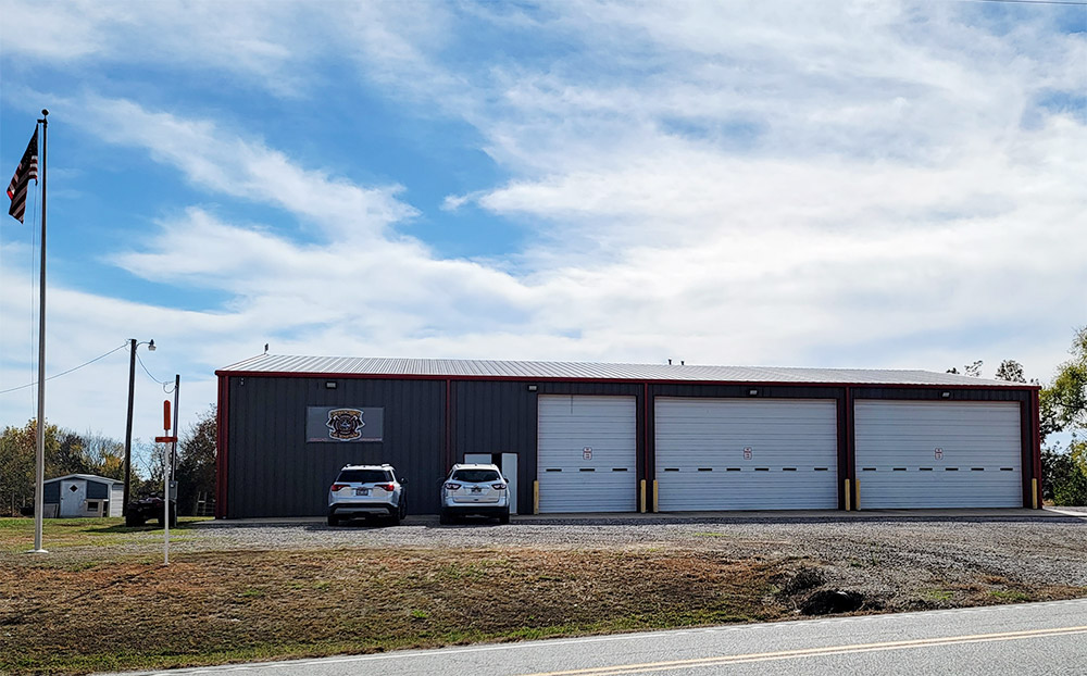 Single story metal fire department building with three garage doors