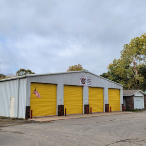 Single story white metal building with four yellow garage doors