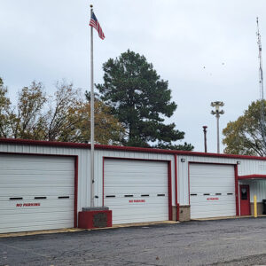 Single story white metal fire department building with three garage doors