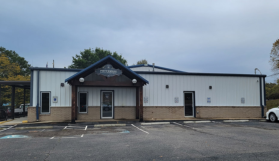Single story brick and metal police building with covered entrance and parking lot