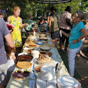 people lined up on both sides of tables with pies on them