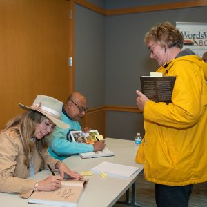 Man and woman sitting at table signing books