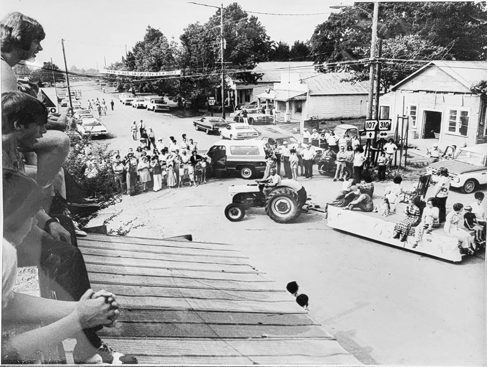 view from above of parade with tractor-drawn float and spectators