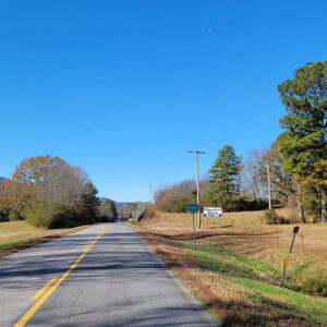 Country road with trees on both sides and hills in distance