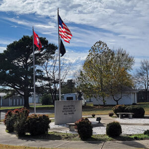 Concrete veterans memorial with benches and flags with buildings and trees around