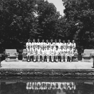 Group of white women and girls dressed in white sitting on two levels of a large stone bench