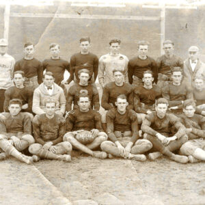 Group of white young men in football uniforms with coach in an Arkansas sweatshirt
