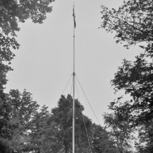 Flagpole in a cemetery surrounded by trees