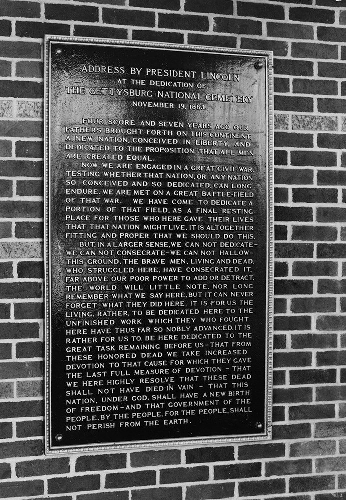 Plaque with words on it attached to brick wall