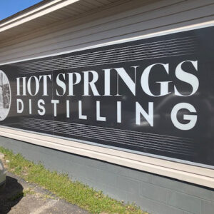 wide black sign saying "Hot Springs Distilling"