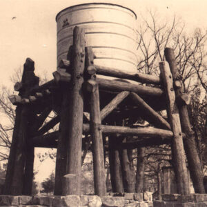 Large tank on a wooden stand with trees in background