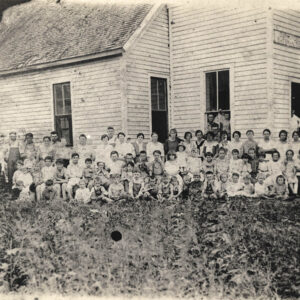 Large group of white children and adults in front of old school building