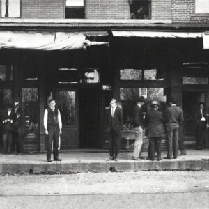 Group of white men standing on sidewalk in front of building