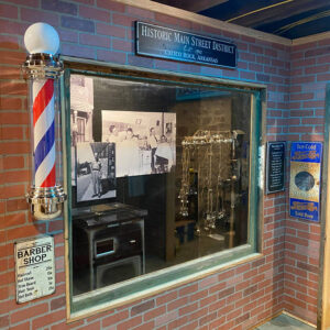 signs and photos and a barber shop pole in a museum display