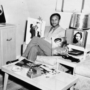 African American man in suit sitting and surrounded by photographs