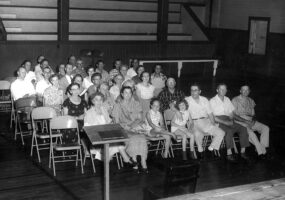 Group of white people sitting in rows of chairs
