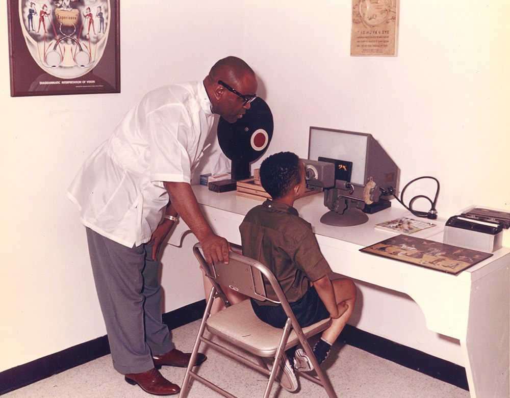 African American man giving African American boy an eye exam at a machine