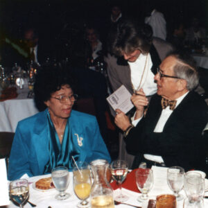 African American woman in a blue outfit and white man in a bow tie at banquet table