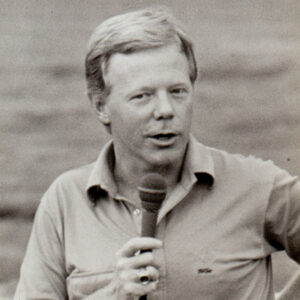 White man in polo shirt holding a microphone