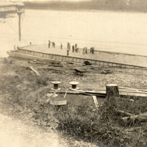 Men standing on a barge floating along the river shore